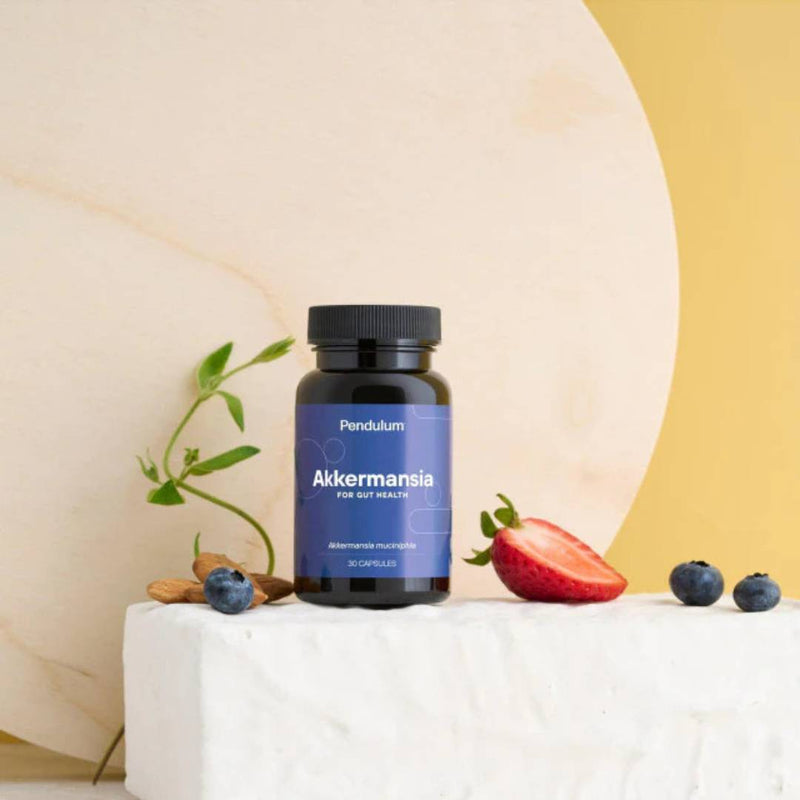 Pendulum Akkermansia probiotic supplement bottle with fresh strawberries, blueberries, and almonds, supporting gut health and digestive balance.
